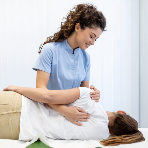 Close up of female osteopath doing shoulder blade therapy on young woman.